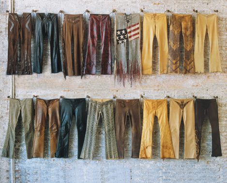 Hand-made Lost Art™ Custom Leather Pants with Leather fringe and Custom Details hanging on wall