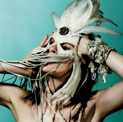 Model Elise Crombez wears a handmade Lost Art™ feather mask adorned with amethyst crystal and is wearing handmade Lost Art™ bracelets made with quartz crystal