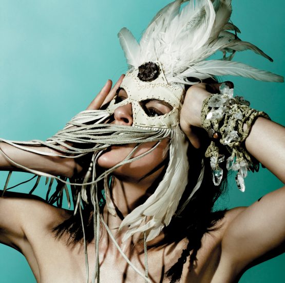 Model Elise Crombez wears a handmade Lost Art™ feather mask adorned with amethyst crystal and is wearing handmade Lost Art™ bracelets made with quartz crystal